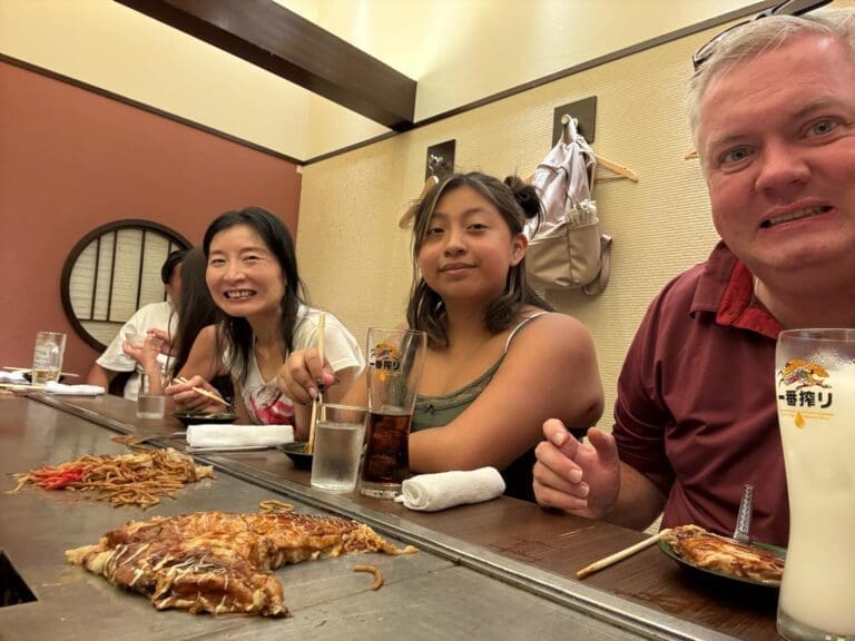 Three individuals seated at a table enjoying a meal with food items placed in front of them.