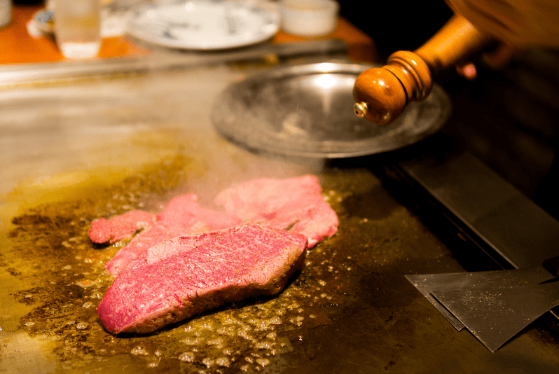 Blogs 16 Kobe beef restaurants, Raw beef steak being cooked on a hot grill with steam rising.