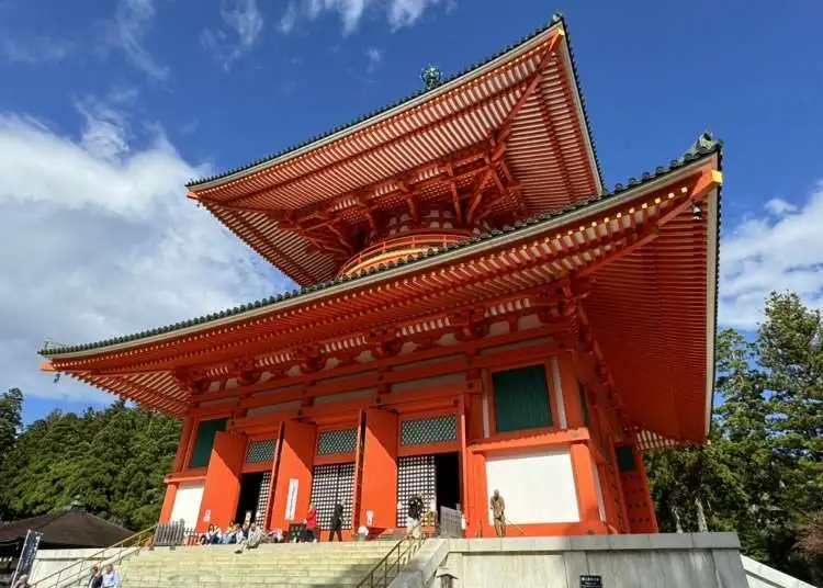 Traditional Japanese temple with a striking red exterior and intricate architectural details against a blue sky.