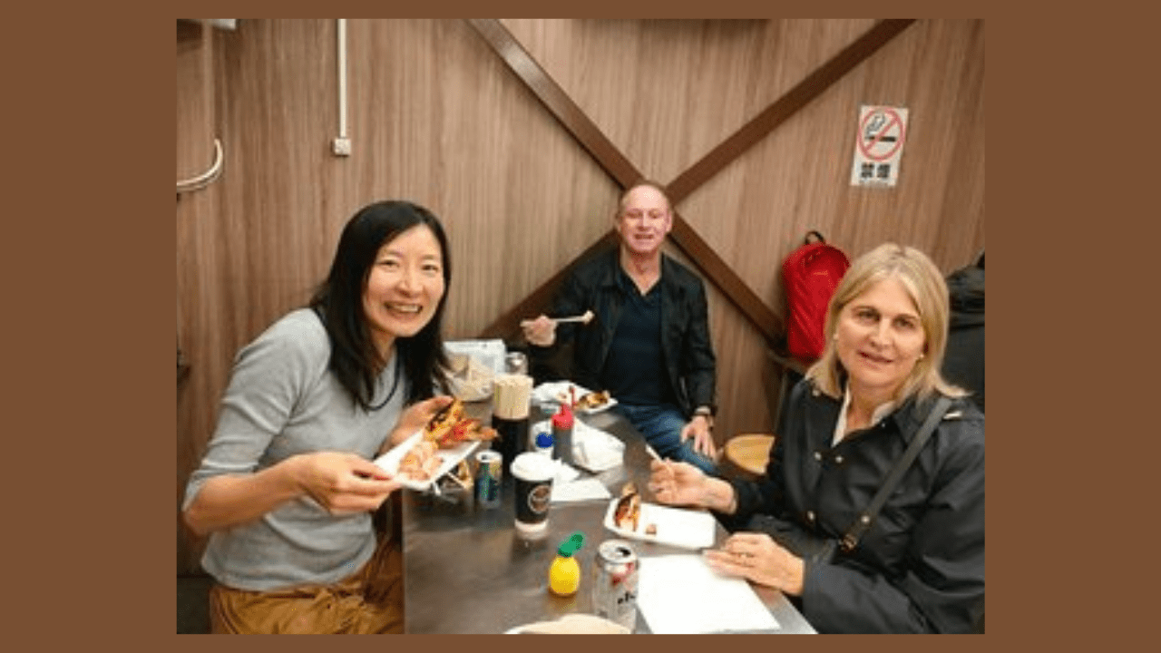 Three individuals enjoying a meal at a table, with food and drinks in front of them.