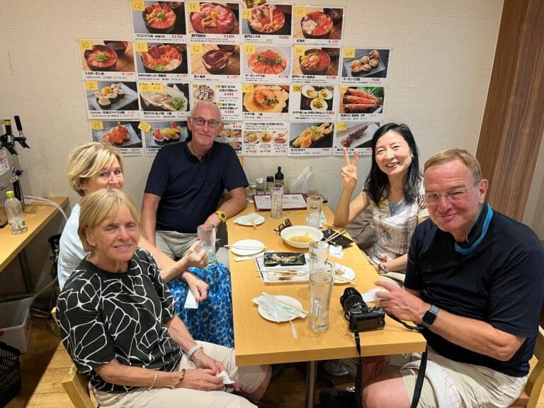 Group of five people seated at a table in a restaurant with a menu displayed on the wall.
